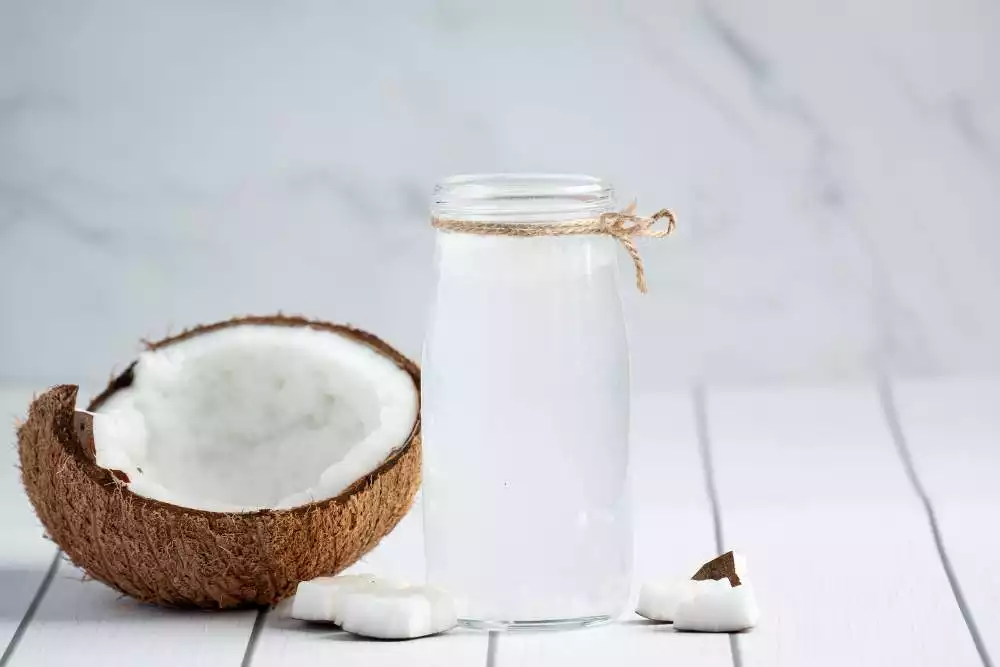coco partido ao meio com uma garrafa de leite de coco ao lado direito