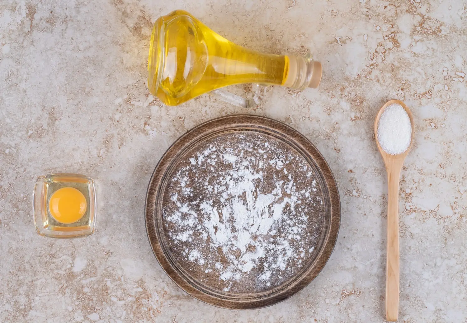 Ingredientes sobre uma superfície clara: bicarbonato de sódio espalhado em um prato de madeira, óleo em uma garrafa de vidro e uma gema de ovo em um recipiente pequeno.