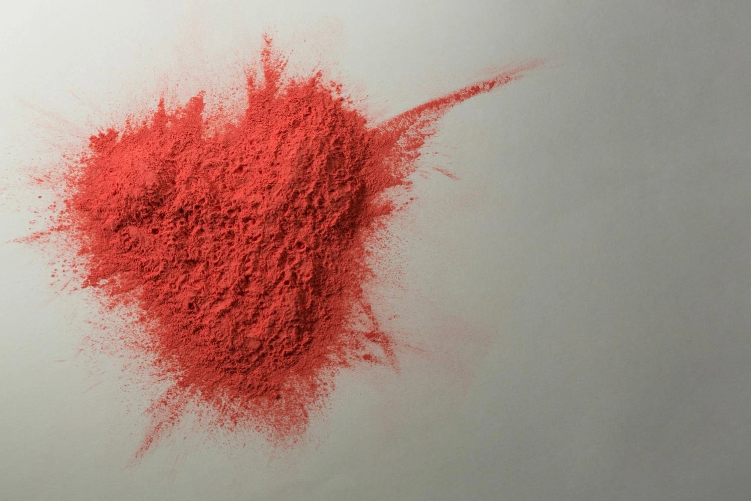 Um montículo de pó de picolinato de cromo espalhado em uma superfície branca, formando um padrão dinâmico. A textura do pó cria uma imagem com detalhes vibrantes e dispersos.